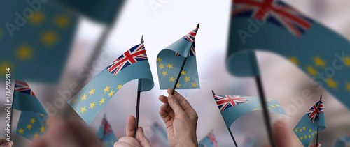 Tuvalu flags in their hands on a blurred urban background