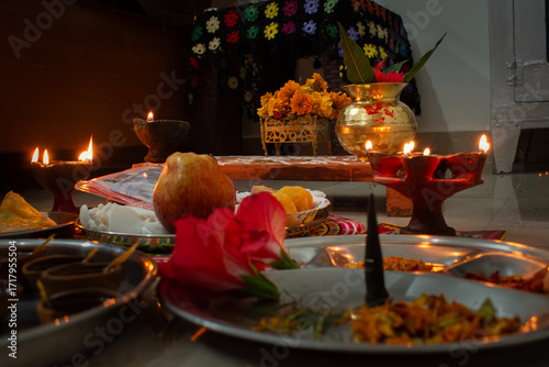 A traditional Hindu pooja setup with lit diyas, flowers, fruits, incense, and offerings arranged for a sacred Diwali ceremony. Lakshmi Ganesh on altar setup