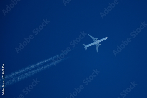 Airplane in the blue sky with contrail. Flight Path Over Blue Sky, travel concept.