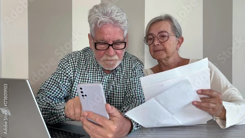 Video call concept. Elderly couple sitting at home talking remotely with doctor on mobile phone webcam to communicate the results of some medical tests,  waits for doctor's consultation