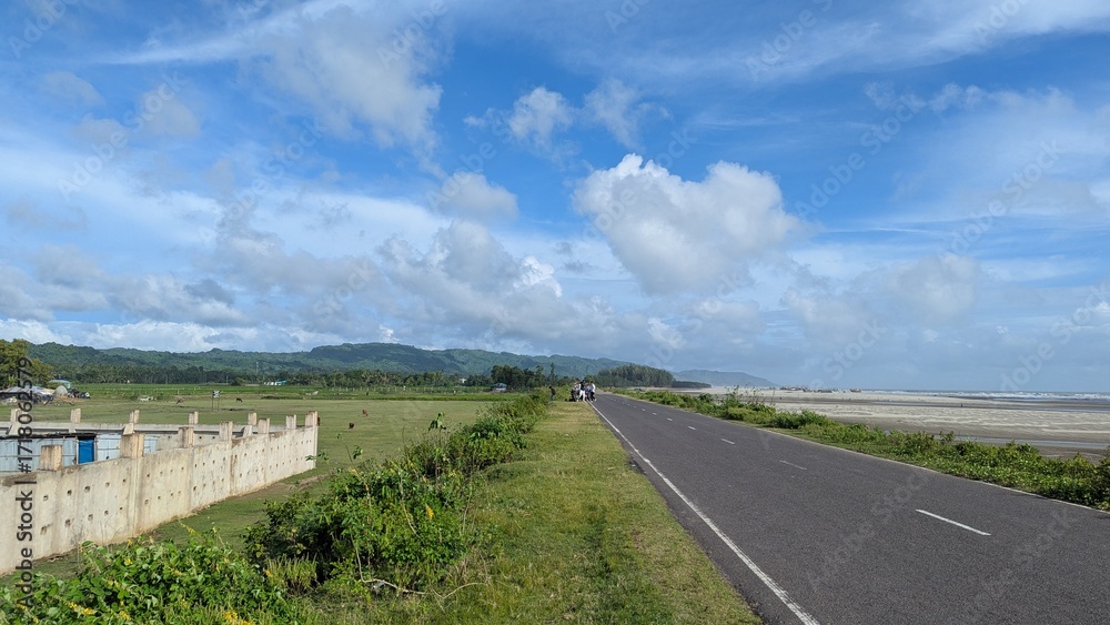 Fototapeta premium Scenic coastal road a picturesque asphalt road stretches along the coastline, offering breathtaking views of the sea, sky, and lush greenery in bangladesh