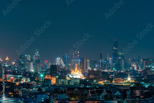 Wallpaper Mural Vibrant city skyline at night featuring glowing skyscrapers, traditional architecture, and bright lights against a dark blue sky. Torontodigital.ca