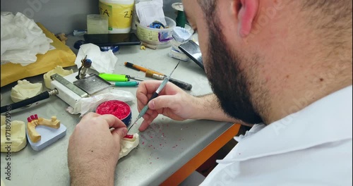 Prosthetics hands while working on the denture, false teeth, a study and a table with dental tools