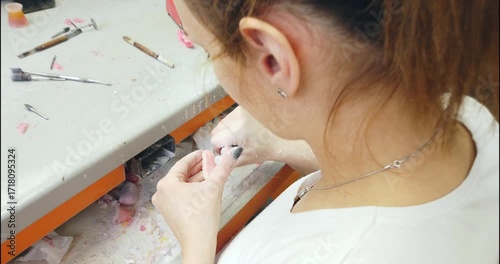 Prosthetics hands while working on the denture, false teeth, a study and a table with dental tools