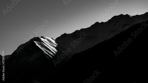 Dramatic black and white mountain landscape with sharp jagged peaks, strong light contrast, deep shadows,