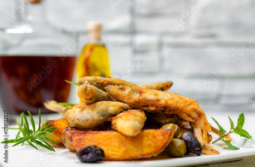 Fried smelt with potatoes and olives. White plate and white background.