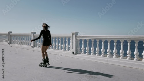 Sporty woman rollerblading outdoors on seafront in a sunny day, active fitness concept.