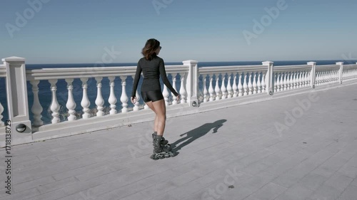 Sporty woman rollerblading on seafront in a sunny day, active fitness concept.