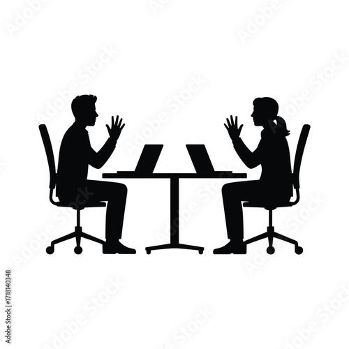 Silhouettes of two people working on laptops at a round table in a modern office.