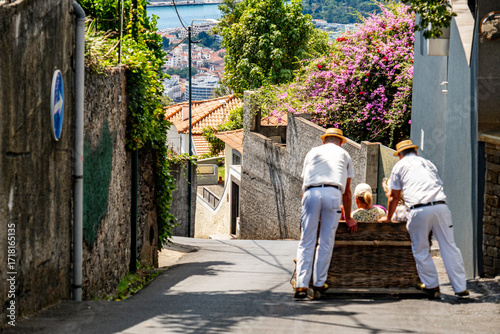Obraz na płótnie Men push wicker toboggan with passenger down Madeira street.