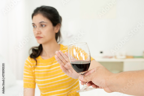 Foto Young woman refusing glass of red wine with hand gesture, showing concept of healthy lifestyle choice, alcohol rejection, sobriety, addiction prevention, wellness, and mindful living at home