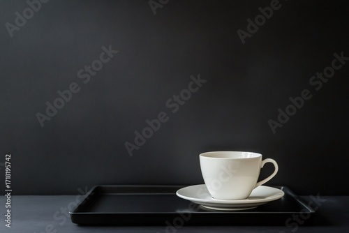 Wallpaper Mural Minimalist still life featuring a white cup and saucer on a black tray, set against a dark background, creating a stark contrast Torontodigital.ca