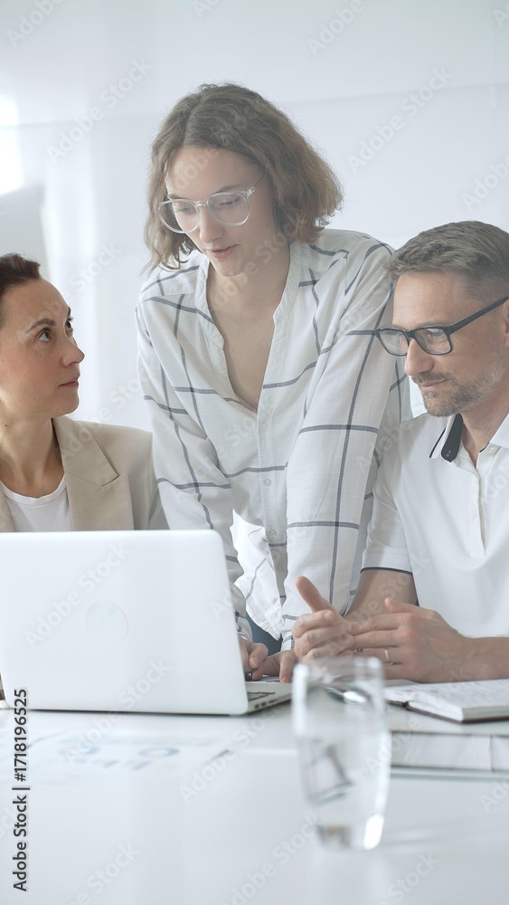 Obraz premium Business people team collaborating on a project, analyzing data on a laptop during a productive office meeting, fostering teamwork and strategic planning