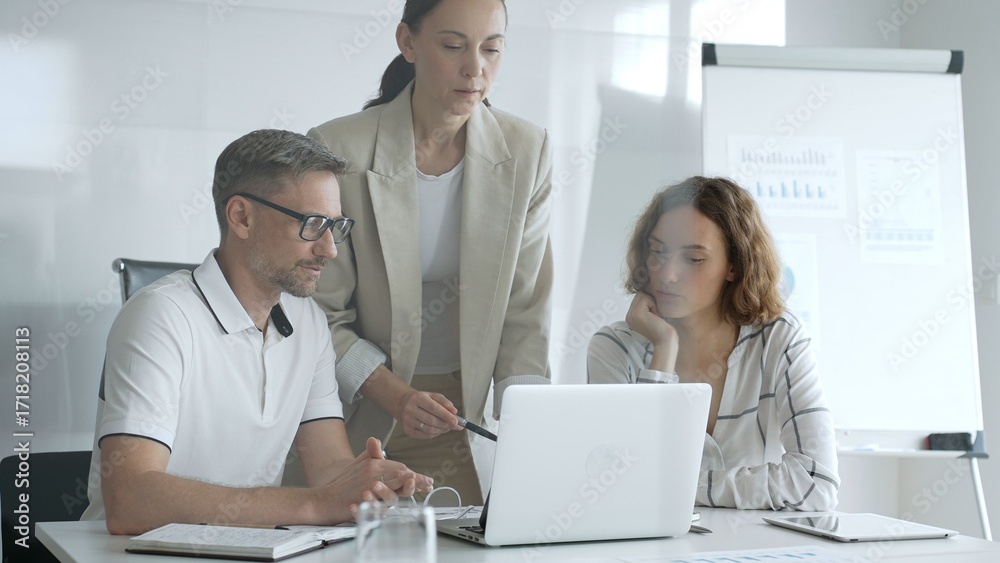 Fototapeta premium Business team collaborating on a project, analyzing data on a laptop during a productive office meeting, demonstrating teamwork and problem solving skills
