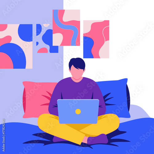 A man in colorful clothes works on a laptop while sitting cross-legged on a bed, with abstract art on the wall.