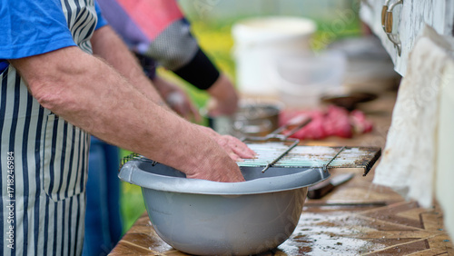 A man washes a dirty grill grate in a basin