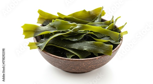 A rustic brown bowl overflows with vibrant, glossy green kelp strips, set against a clean white background.