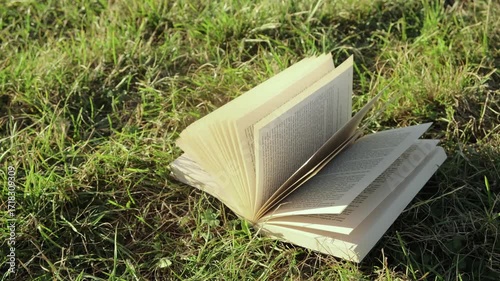An open book lies on the grass as warm sunlight slides across its pages. Peaceful and cozy lifestyle scene, perfect for relaxation, study, and nature-inspired moments.