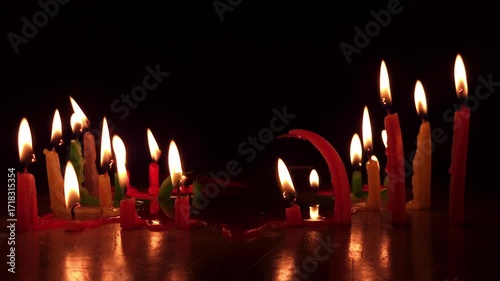 Glowing candle flame flickers in the dark night, its warm light reflecting on the surface during a joyful celebration in the church, as candles burn brightly for a holiday party, birthday, Christmas.