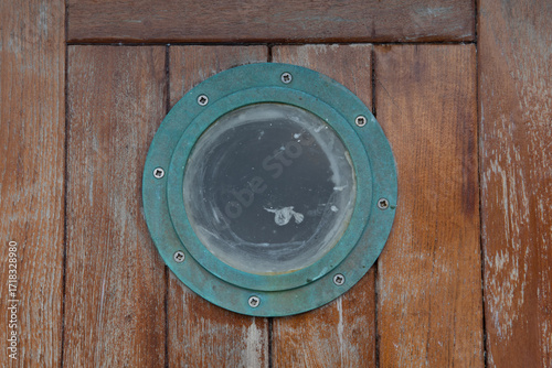 Weathered ship porthole with patina on wooden surface