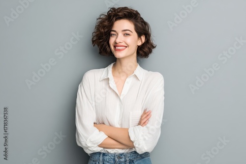 Happy cheerful young woman with curly hair smiling in casual white shirt portrait.