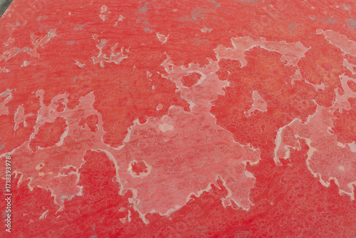 Sun damaged, faded, and peeling red paint on a car