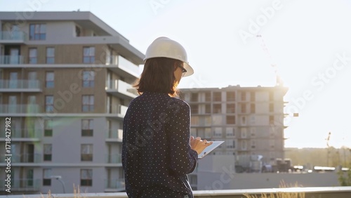 Принти на полотні Female constructive architect wearing a white helmet is taking notes with a tabl