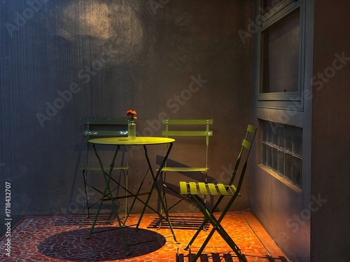 Tableau sur toile A cozy, dimly lit balcony with a small yellow bistro table and matching chairs, creating an intimate and peaceful atmosphere