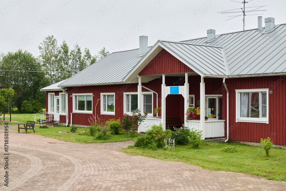Obraz premium Charming Red Cottage Surrounded by Lush Greenery, Featuring a Welcoming and Inviting Entrance