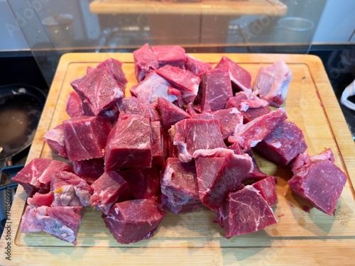 Carne em cubos cortas sobre a mesa com fundo desfocado e cebolas e panela con nivel de agua.