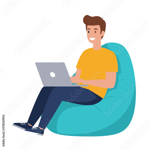 A smiling young man in casual clothing sits comfortably on a large, teal beanbag chair, actively typing on a silver laptop computer.