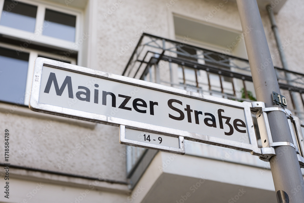 Obraz premium Mainzer Strasse street name sign in Berlin, Germany. Road signage at the intersection. Close up of the location guide showing the direction of the street in Friedrichshain.