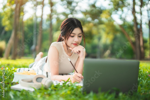 Wallpaper Mural A young woman enjoys spending time writing and reading in the park. Torontodigital.ca