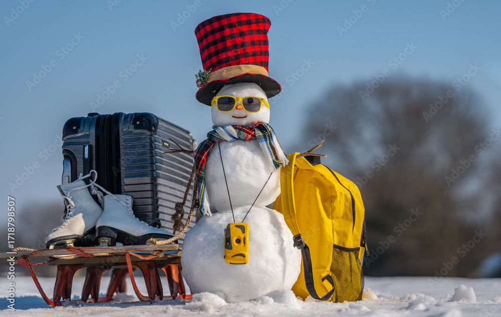 Obraz premium Snowman traveler with backpack on snowy adventure. Festive snowman tourist wearing sunglasses outdoors. Winter journey with snowman and holiday decorations. Snowman ready for New Year trip with