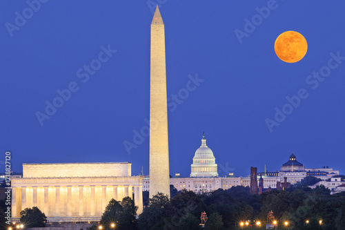 Washington DC skyline illuminated at dusk with Lincoln Memorial, Washington Monument and US Capitol, including a beautiful full orange moon on the background, USA