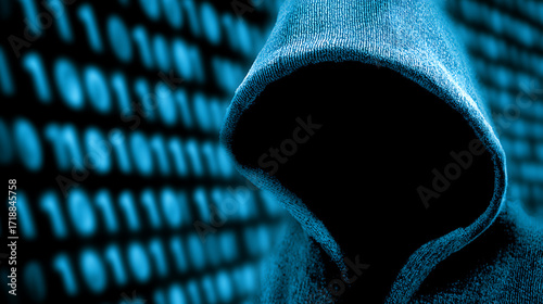 Silhouetted figure in a hooded sweatshirt against a background of binary code, suggesting cybercrime or digital anonymity.