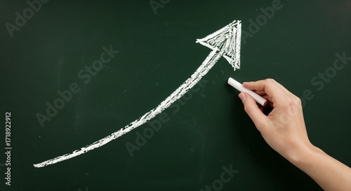 Hand drawing upward arrow with chalk on blackboard  