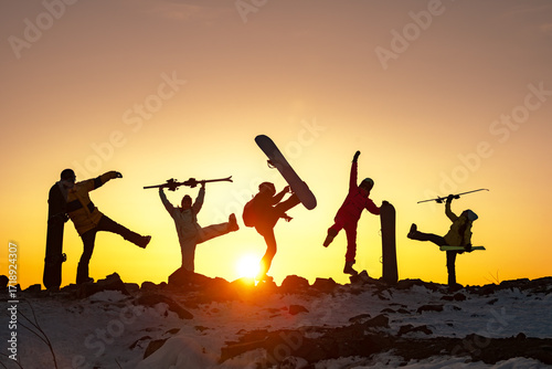 Fotografia Group of happy young friends skiers and snowboarders are having fun at sunset mo