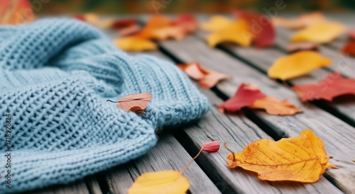 Cozy Blue Sweater Draped Over Wooden Surface Surrounded by Autumn Leaves on a...