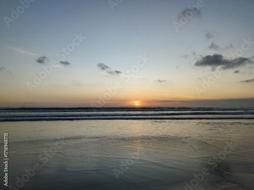 Scenic beach sunset with colorful sky, gentle waves, and serene horizon. Perfect natural background for travel, vacation, and tropical landscape themes.