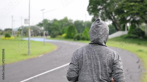 Asian female athlete jogs at sunrise in park—slow-motion highlights graceful stride, fresh air, and morning wellness in lush green surroundings.