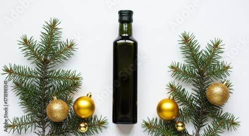 Bottle of olive oil surrounded by pine branches and golden Christmas ornaments on a white background, copy space
