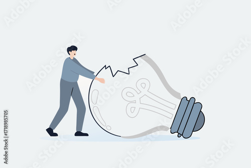depressed businessman standing with old broken light bulb idea that failed miserably.