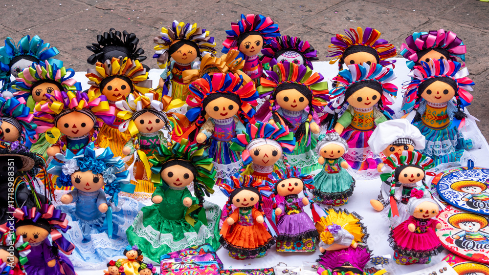 Fototapeta premium A table is filled with a variety of dolls, each with unique outfits and accessories. Historic center of Queretaro City, decorations and traditions to celebrate Mexico's Independence Day, colonial arch