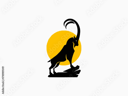 Majestic black ibex silhouette stands proudly on rocky outcrop against a vibrant golden sun