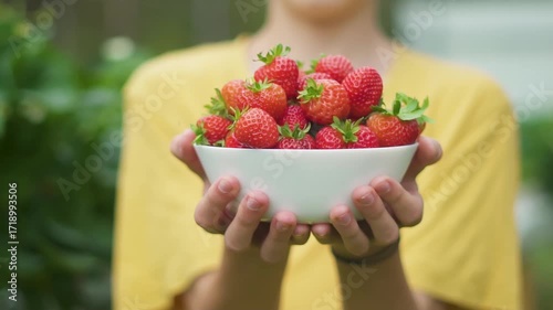 Baby child toddler teenager holding plate of strawberries. Close up focus on fresh berries. Healthy snack, rich in vitamins. Natural food from garden harvest, symbol of organic farming.