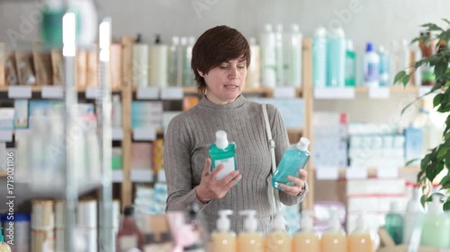 Interested female customer choosing mouthwash at pharmacy. High quality 4k footage