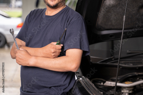 An Asian man and his tools are maintaining his car by himself.