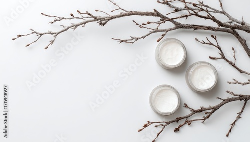 Wallpaper Mural Three jars of cream-colored face cream, nestled amongst dry, light brown branches on a bright white background Torontodigital.ca