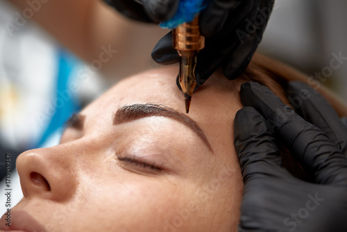 Vászonkép Expert artist applies semi-permanent makeup to enhance eyebrows in a beauty stud